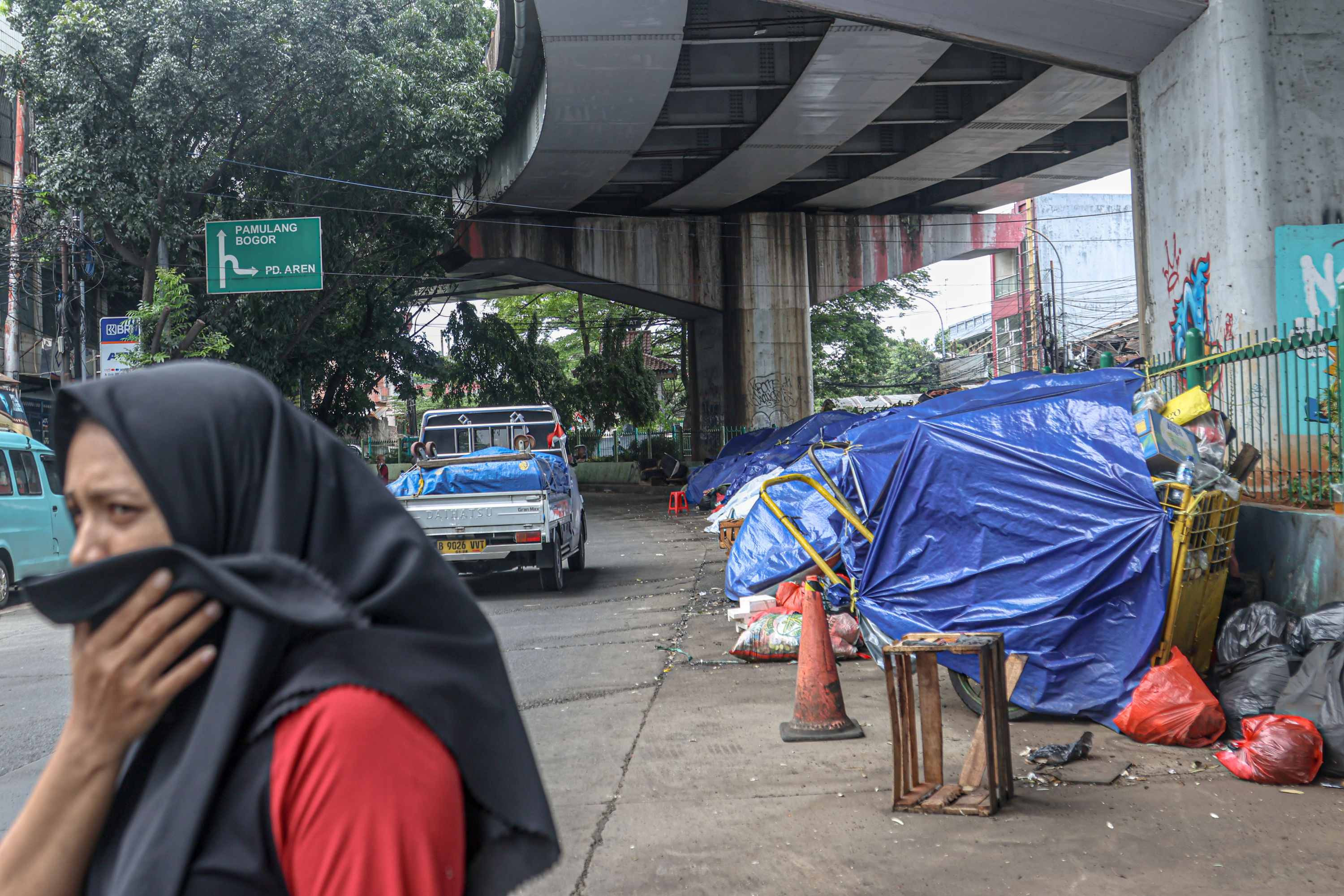 Aktifitas warga di sekitar tumpukan sampah di Jalan Dewi Sartika, Ciputat, Tangerang Selatan, Selasa (16/12/2025). Sampah yang menumpuk di pinggir jalan tersebut disebabkan adanya penataan gunungan sampah di Tempat Pembuangan Akhir (TPA) Cipeucang sehingg
