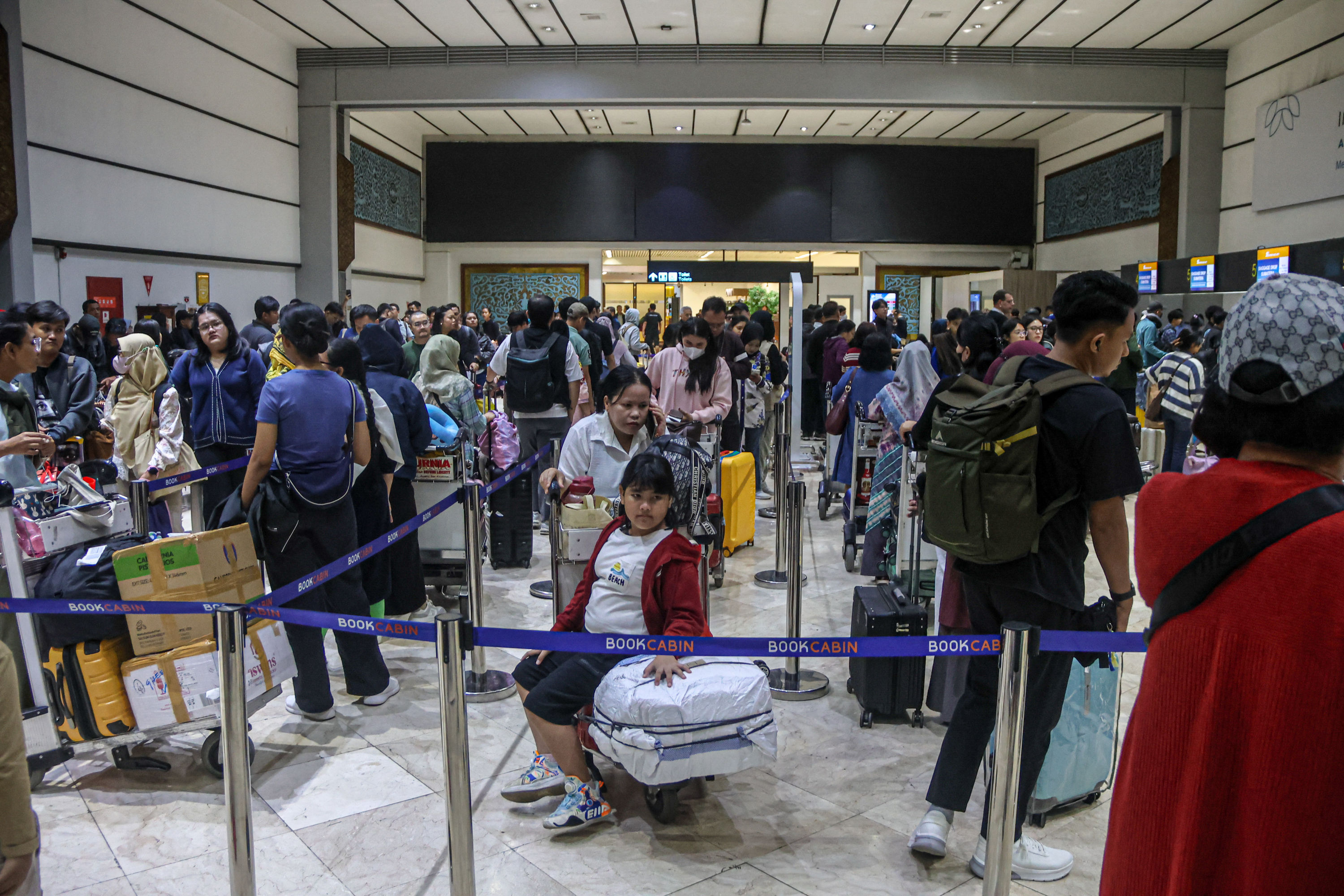 Penumpang mengantri di depan konter check-in di Terminal 2, Bandara Soekarno-Hatta, Tangerang, Sabtu (20/12/2025). PT Angkasa Pura Indonesia (InJourney Airports) Kantor Cabang Bandara Internasional Soekarno-Hatta (Soetta) memperkirakan hari ini Sabtu (20/