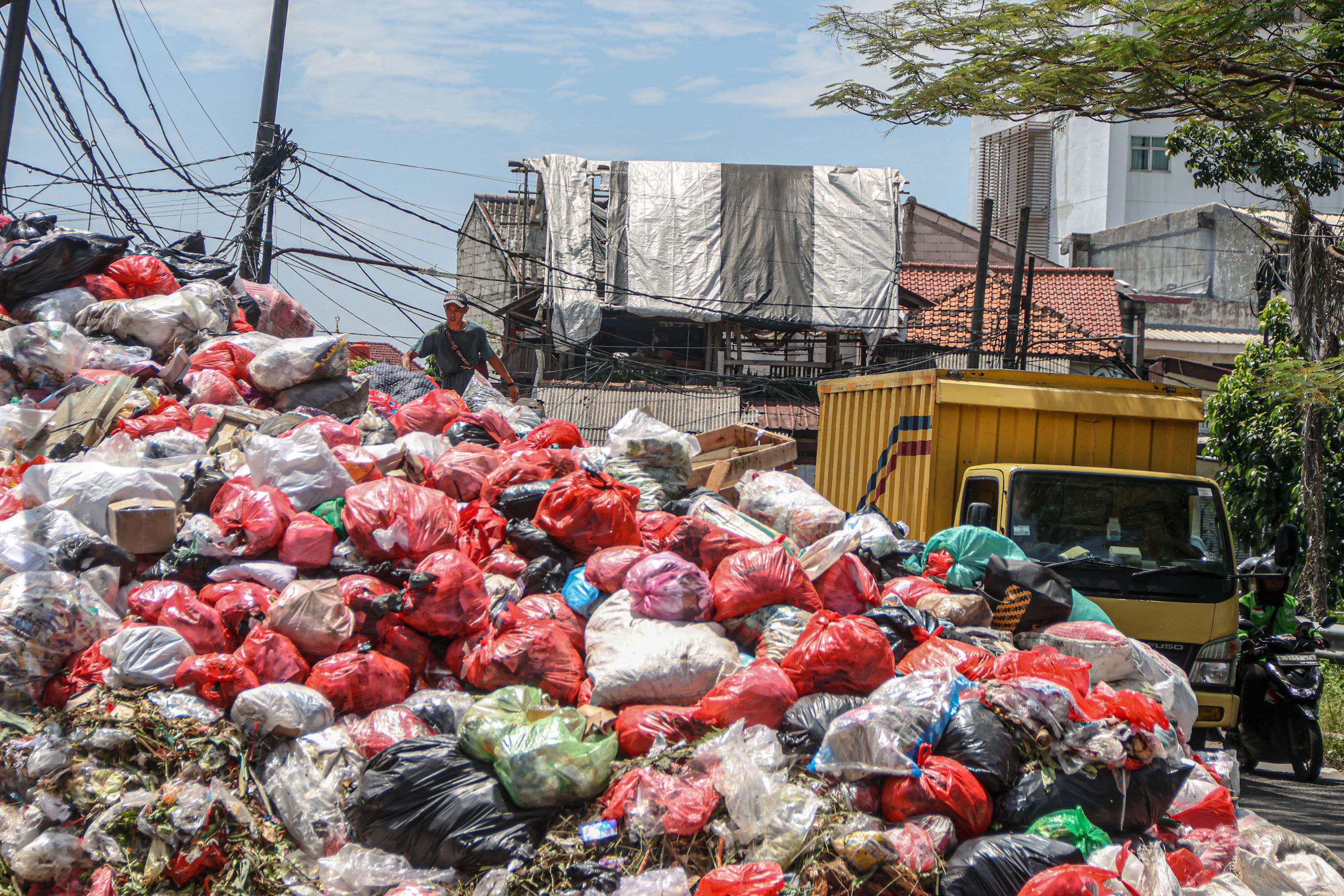 Sejumlah pengendara melintas di tumpukan sampah yang berada di depan pasar Cimanggis, Tangerang Selatan, Selasa (06/01/2025). Tumpukan sampah yang mencapai tiga meter tersebut dikarenakan masih belum optimalnya TPA Cipeucang untuk menampung sampah dari Ta