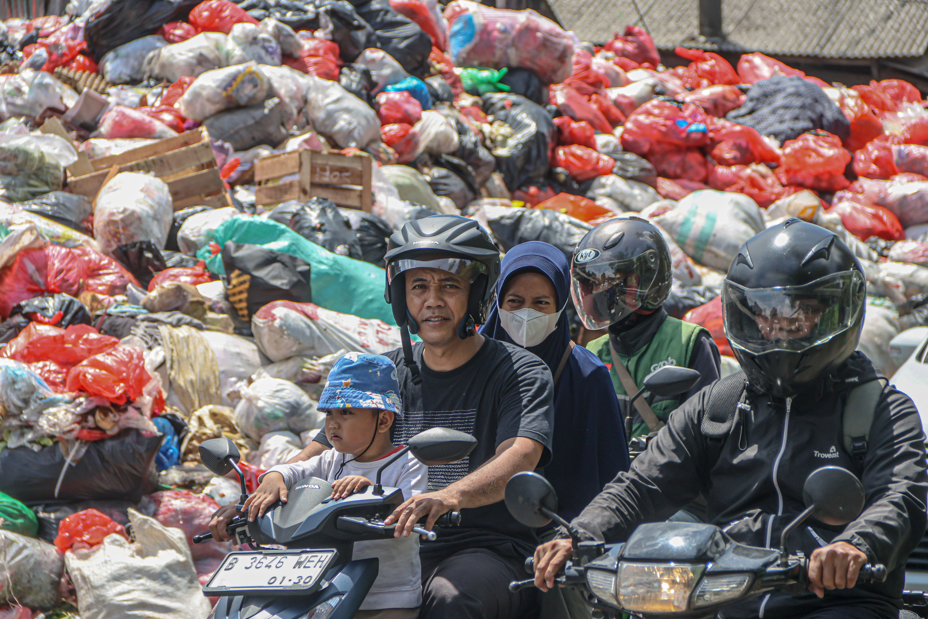Sejumlah pengendara melintas di tumpukan sampah yang berada di depan pasar Cimanggis, Tangerang Selatan, Selasa (06/01/2025). Tumpukan sampah yang mencapai tiga meter tersebut dikarenakan masih belum optimalnya TPA Cipeucang untuk menampung sampah dari Ta