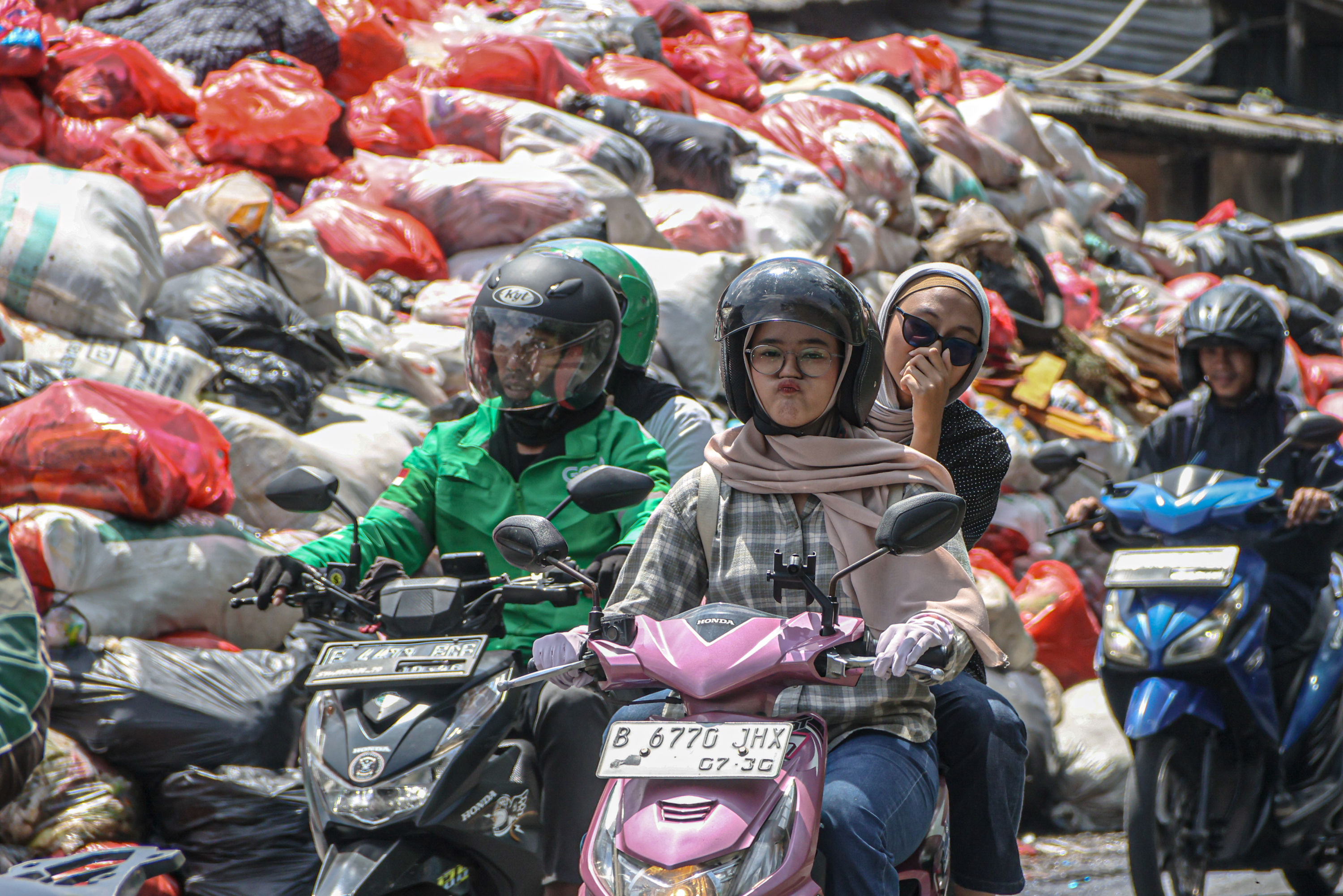 Sejumlah pengendara melintas di tumpukan sampah yang berada di depan pasar Cimanggis, Tangerang Selatan, Selasa (06/01/2025). Tumpukan sampah yang mencapai tiga meter tersebut dikarenakan masih belum optimalnya TPA Cipeucang untuk menampung sampah dari Ta