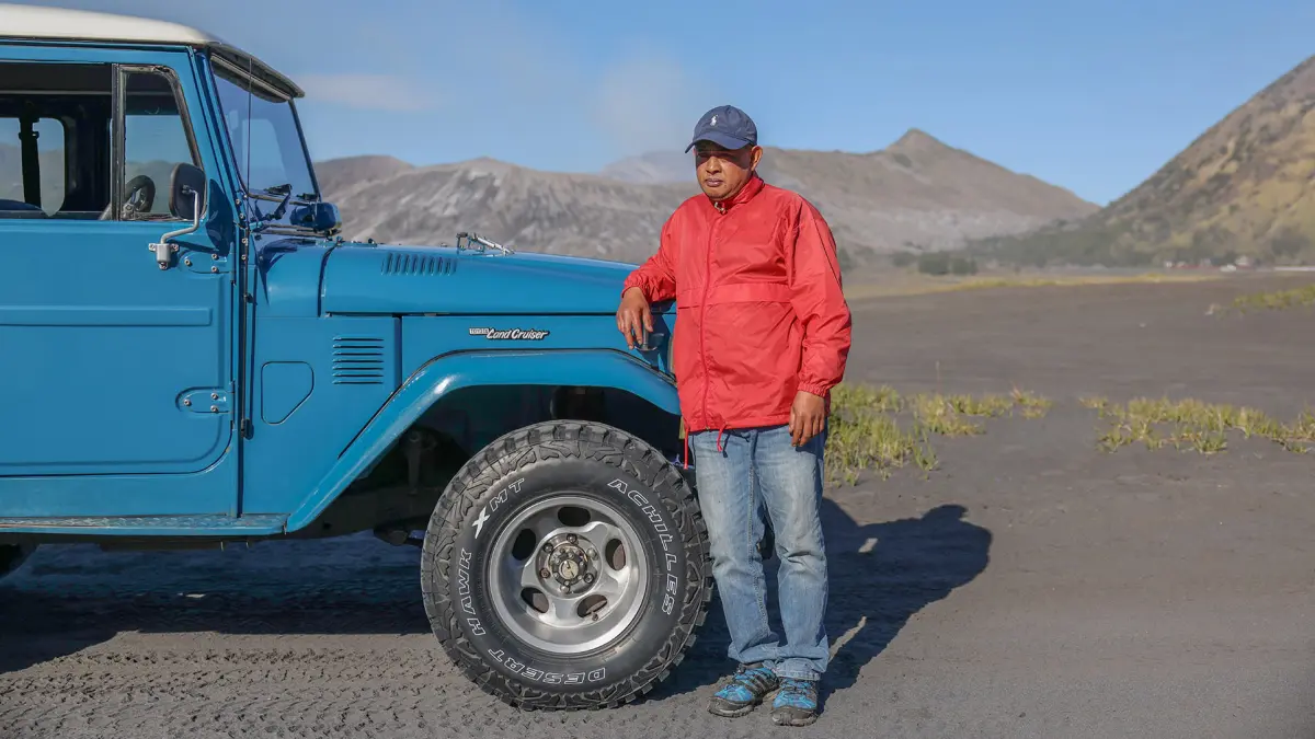 Imam Slamet berpose di depan Toyota Land Cruiser FJ40 miliknya di lautan pasir Bromo (29/5/2026). (Foto: Hendra/JawaPos.com)