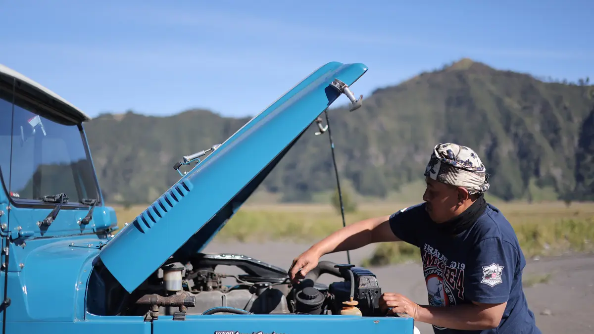 Imam Slamet mengecek Toyota Land Cruiser FJ40 miliknya di lautan pasir Bromo (29/5/2026). (Foto: Hendra/JawaPos.com)