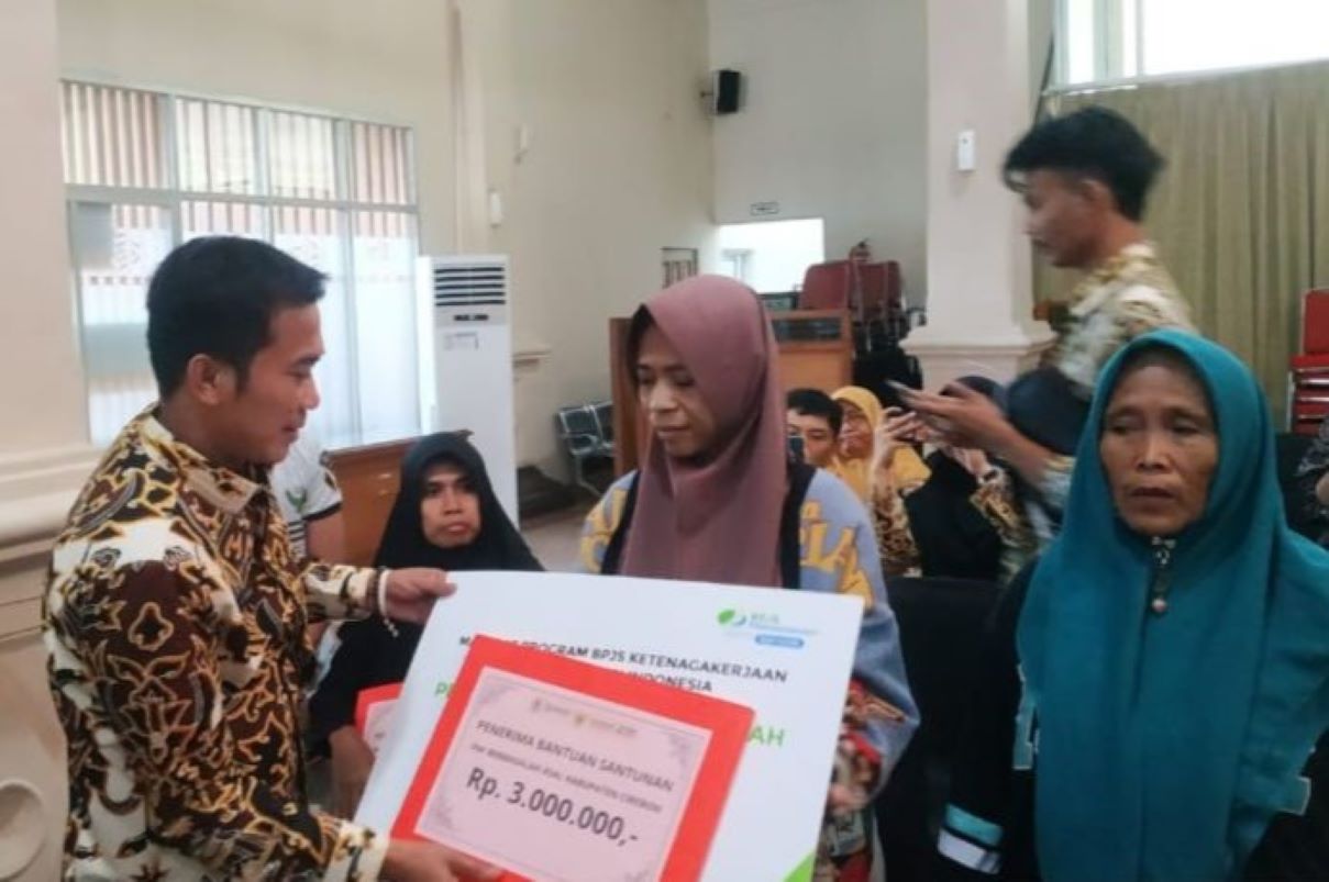 Wakil Bupati Cirebon Agus Kurniawan (kiri) beri santunan kepada keluarga pekerja migran di Cirebon, Kamis (8/5). (Fathnur Rohman/Antara)