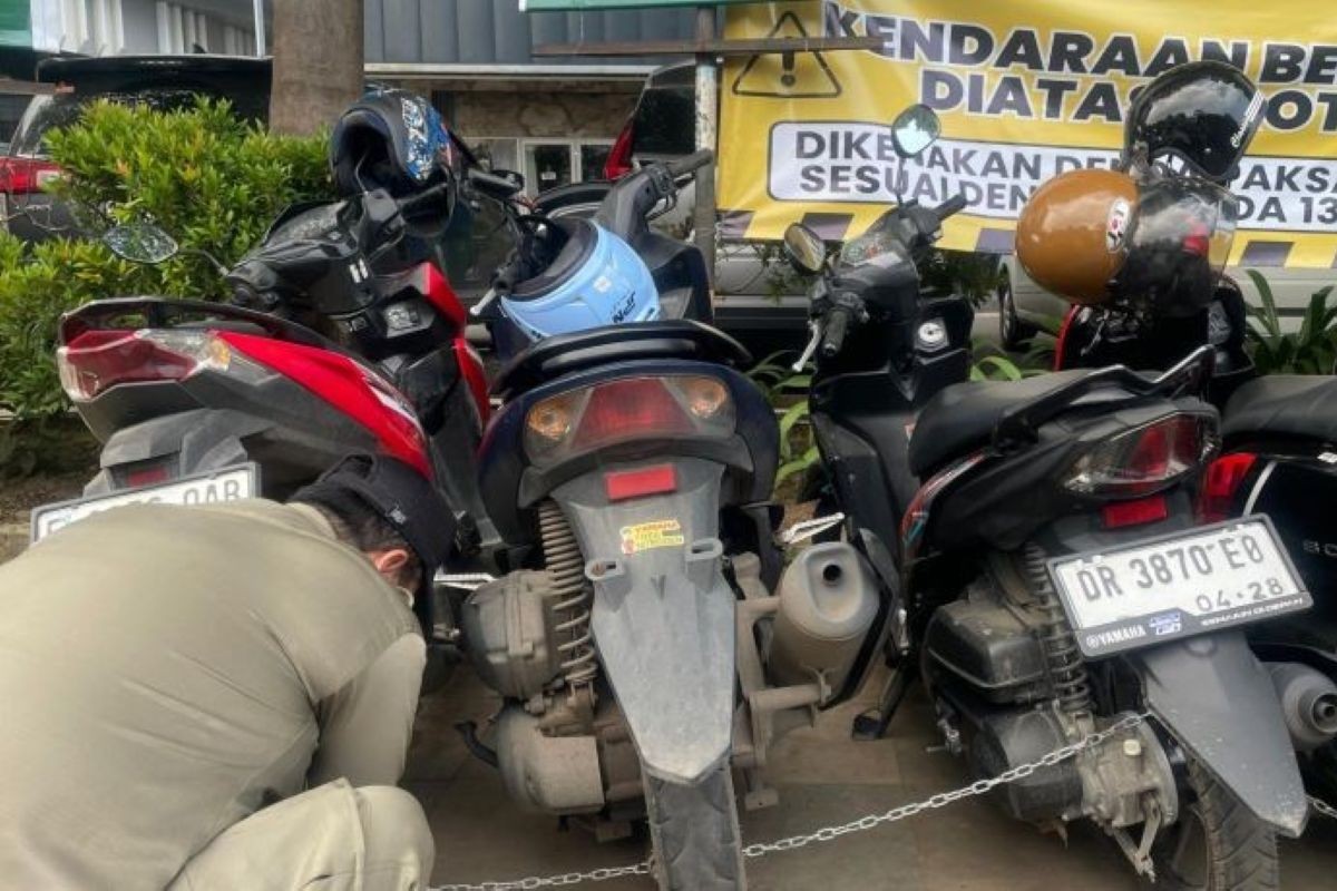 Petugas merantai kendaraan yang parkir di trotoar dan bahu jalan di Kota Cirebon. (Fathnur Rohman/Antara)