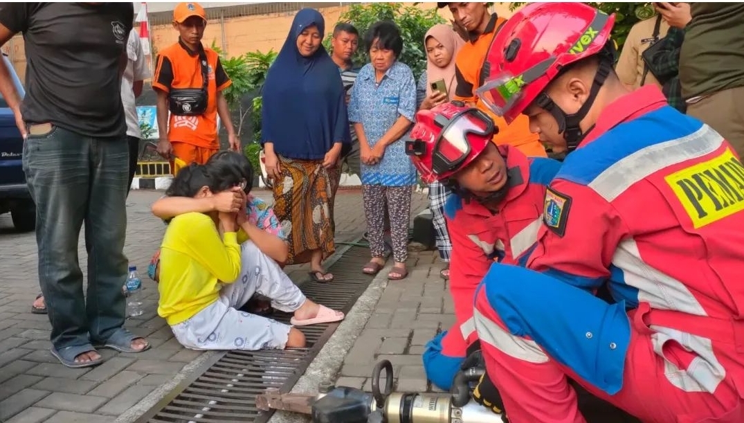 BERLANGSUNG DRAMATIS: Petugas Damkar Ciracas berusaha mengeluarkan kaki kanan anak 10 tahun yang terjeblos ke saluran air. (Yogi Wahyu Priyono/Jawa Pos)
