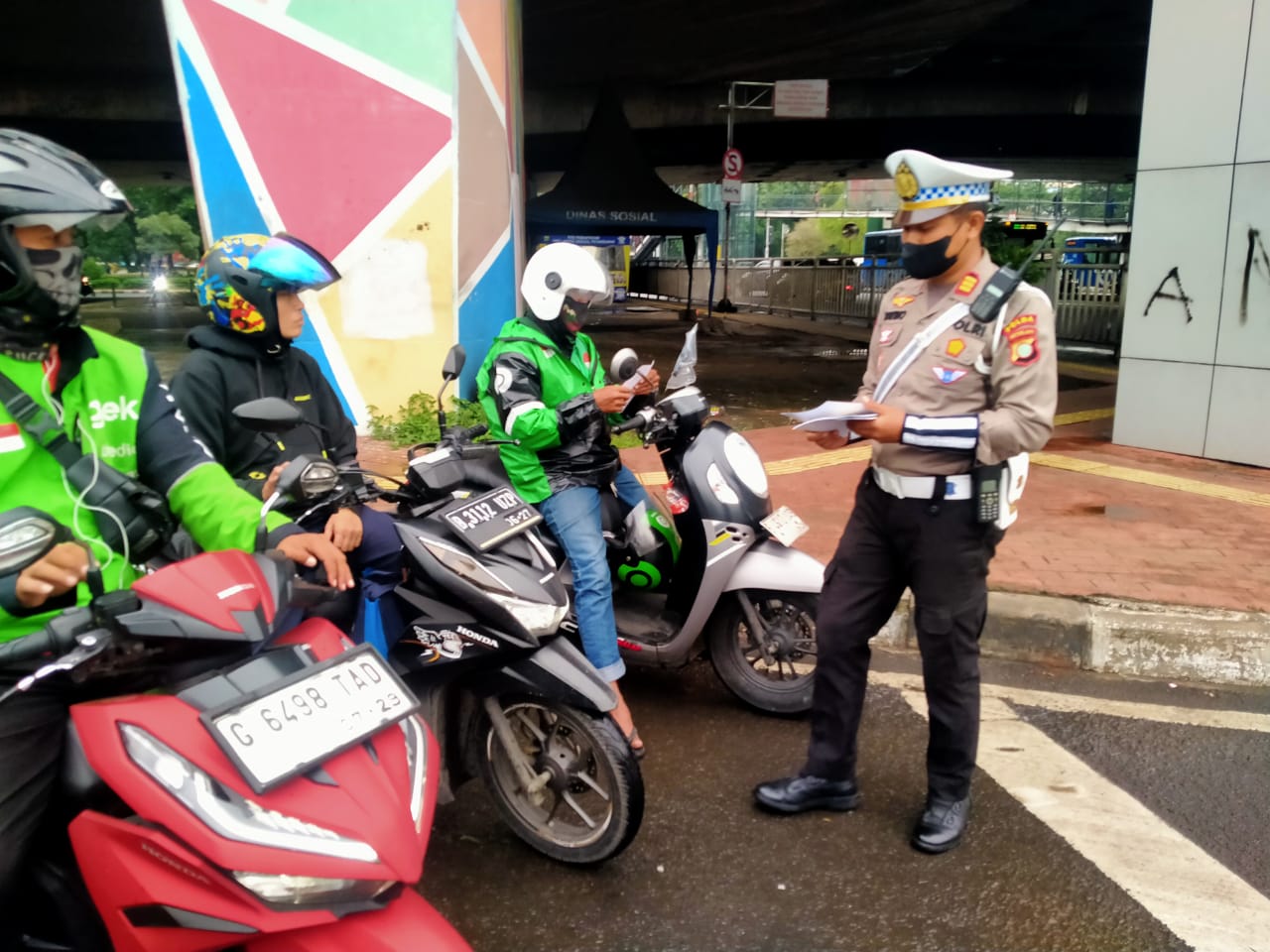 Petugas kepolisian menilang pengendara sepeda motor yang melanggar lalu lintas.