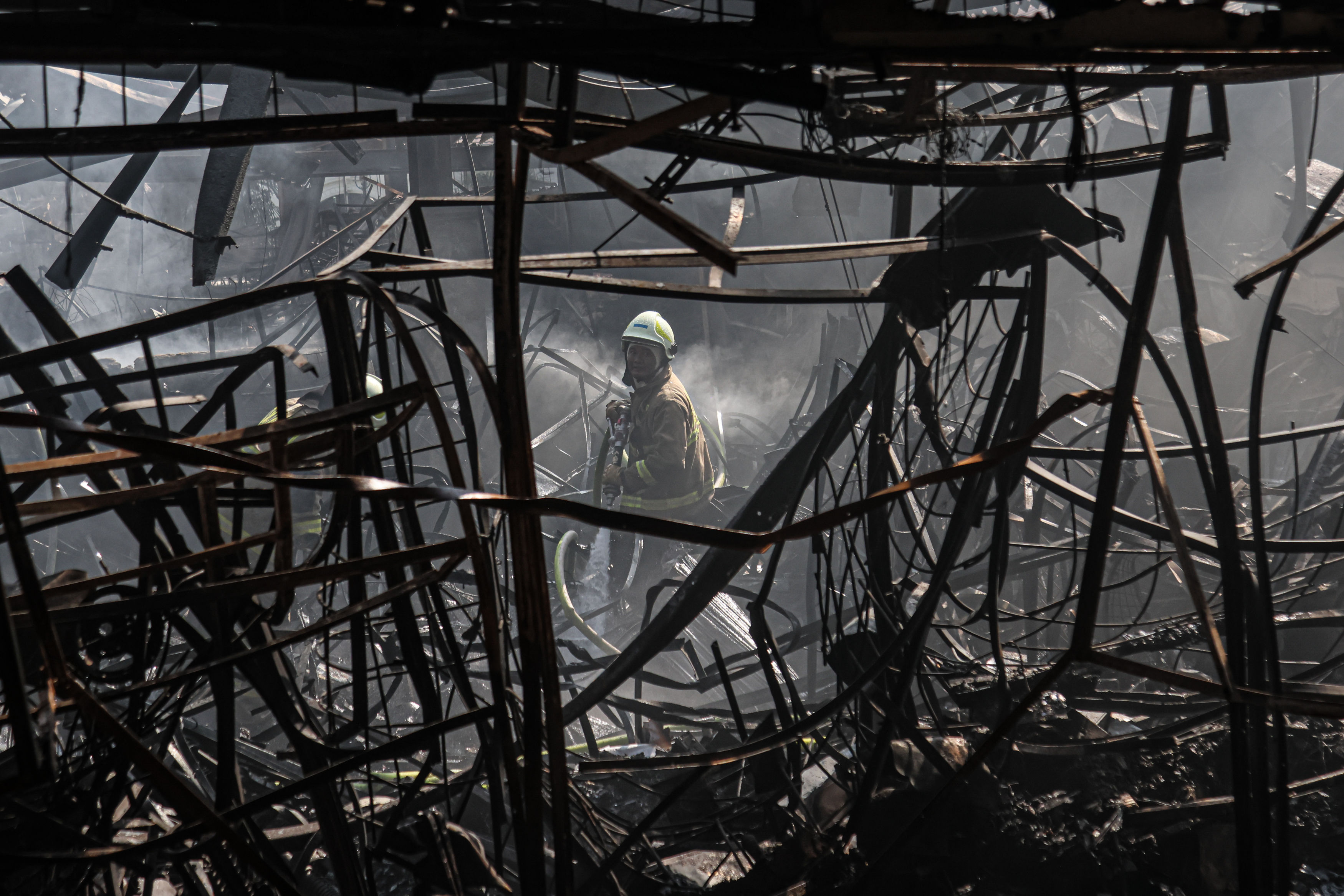 Petugas pemadam kebakaran melakukan pendinginan di pasar Taman Puring yang terbakar di Jakarta, Selasa (29/07/2025). Kebakaran yang terjadi sejak semalam mengakibatkan setidaknya 500 kios yang berjualan pakaian, sepatu, serta peralatan elektronik ludes te