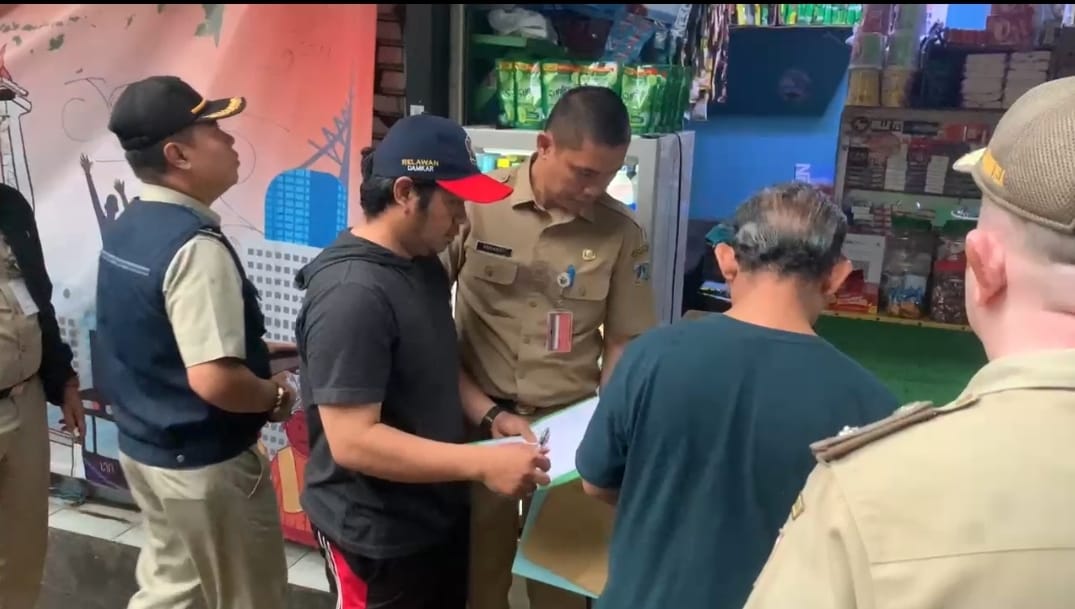 Petugas Satpol PP Jakarta Selatan membantu merelokasi pedagang di Jalan Barito.