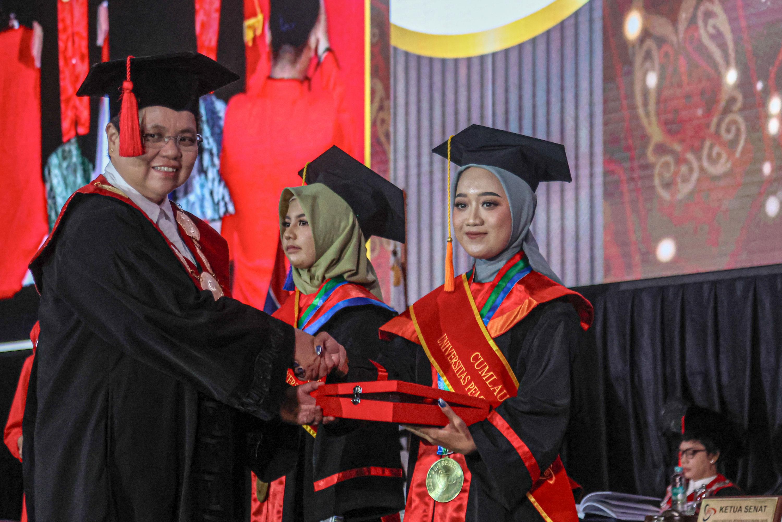 Rektor UPJ Prof. Elisabeth Rukmini (kiri) memberikan penghargaan kepada wisudawan/wisudawati saat Wisuda ke-11 dan Dies Natalis ke-14 di Ecovention Hall, Ancol, Jakarta.