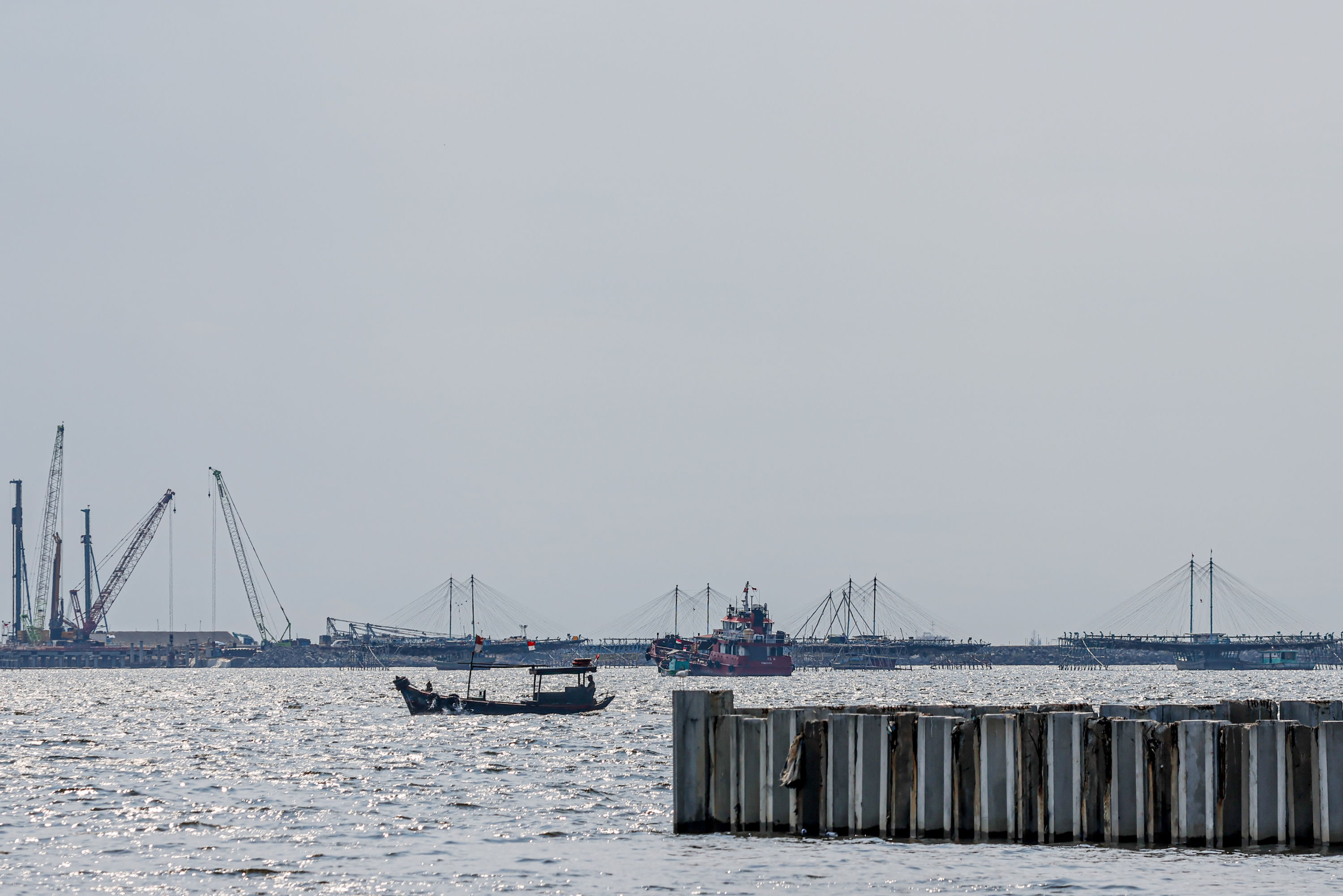 Sejumlah pekerja beraktifitas di sekitar pembangunan tanggul beton pemecah gelombang di pelabuhan PT. Karya Citra Nusantara di Cilincing, Jakarta.