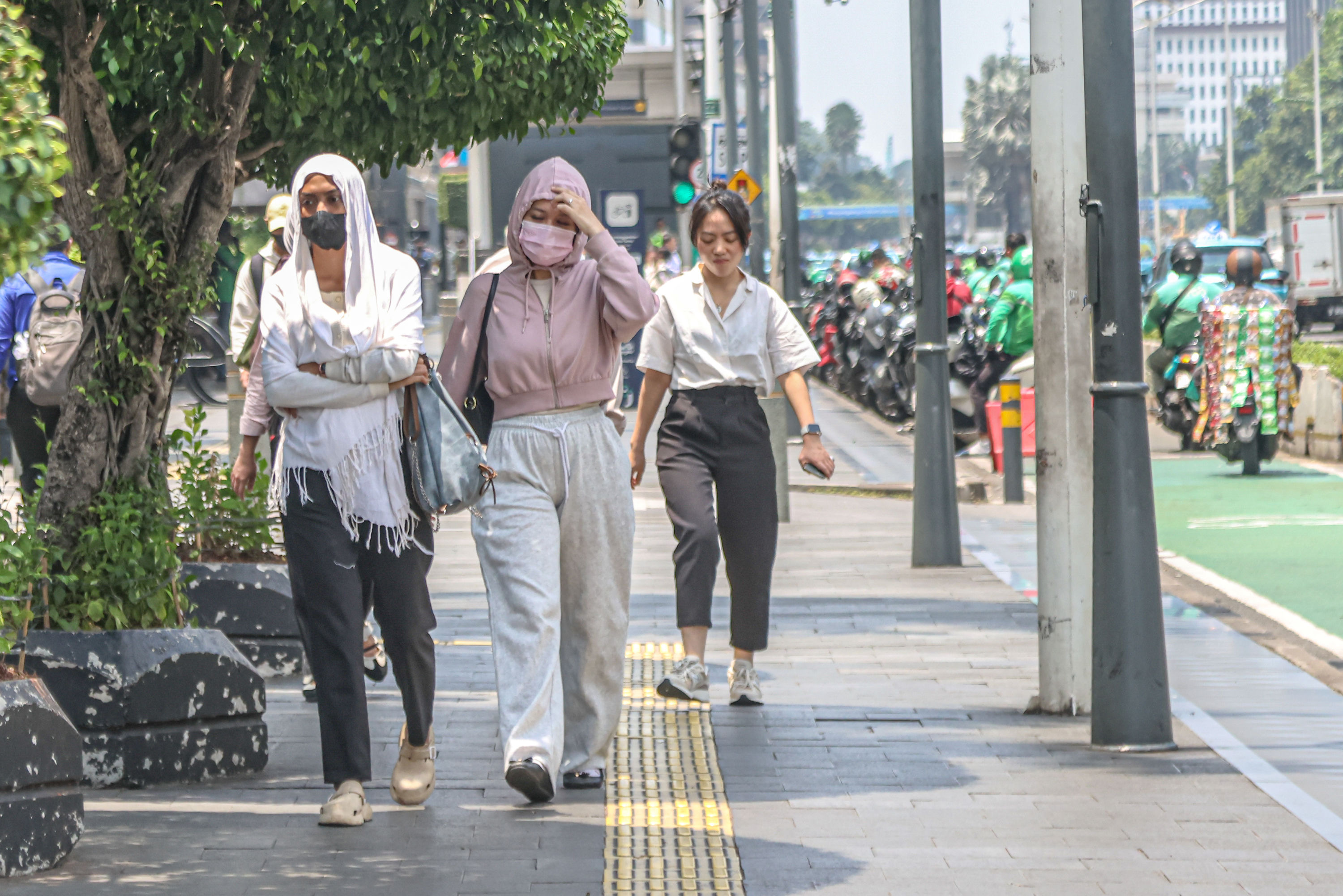 Pejalan kaki menggunakan jaket untuk melindungi dari panas di sekitar Bundaran HI, Jakarta Pusat.