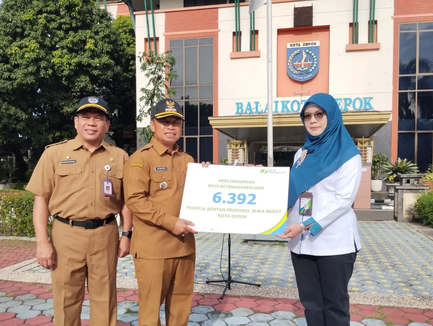 Kepala BPJS Ketenagakerjaan Kota Depok Novarina Azli menyerahkan stimulan BPJS kepada Wali Kota Depok Supian Suri, saat apel pagi di Balai Kota pada Senin (24/11).