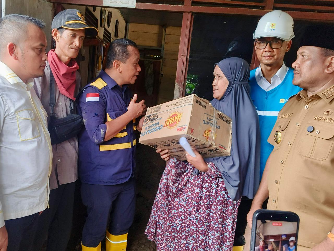 Menteri ESDM Bahlil Lahadalia (tiga dari kiri), Bupati Bireuen Mukhlis (kanan), dan Dirut PLN Darmawan Prasodjo (dua dari kanan) memberikan bantuan sembako kepada warga Desa Blang Panjo, Aceh.
