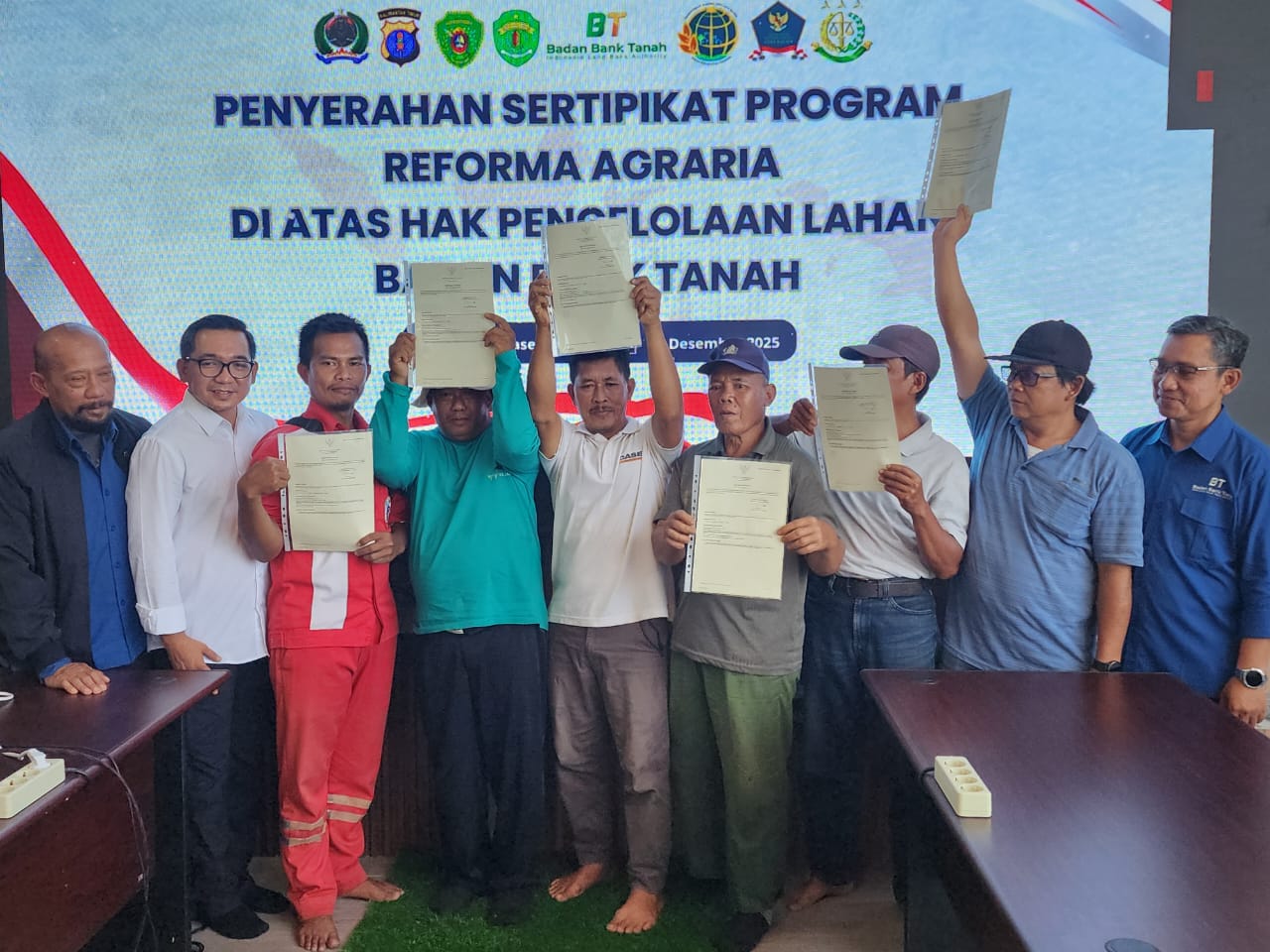 Warga Kelurahan Gresik penerima lahan dalam program reforma agraria mengangkat sertifikat hak pakai di atas hak pengelolaan Badan Bank Tanah di kantor BBT, Penajam Paser Utara hari ini (4/12).