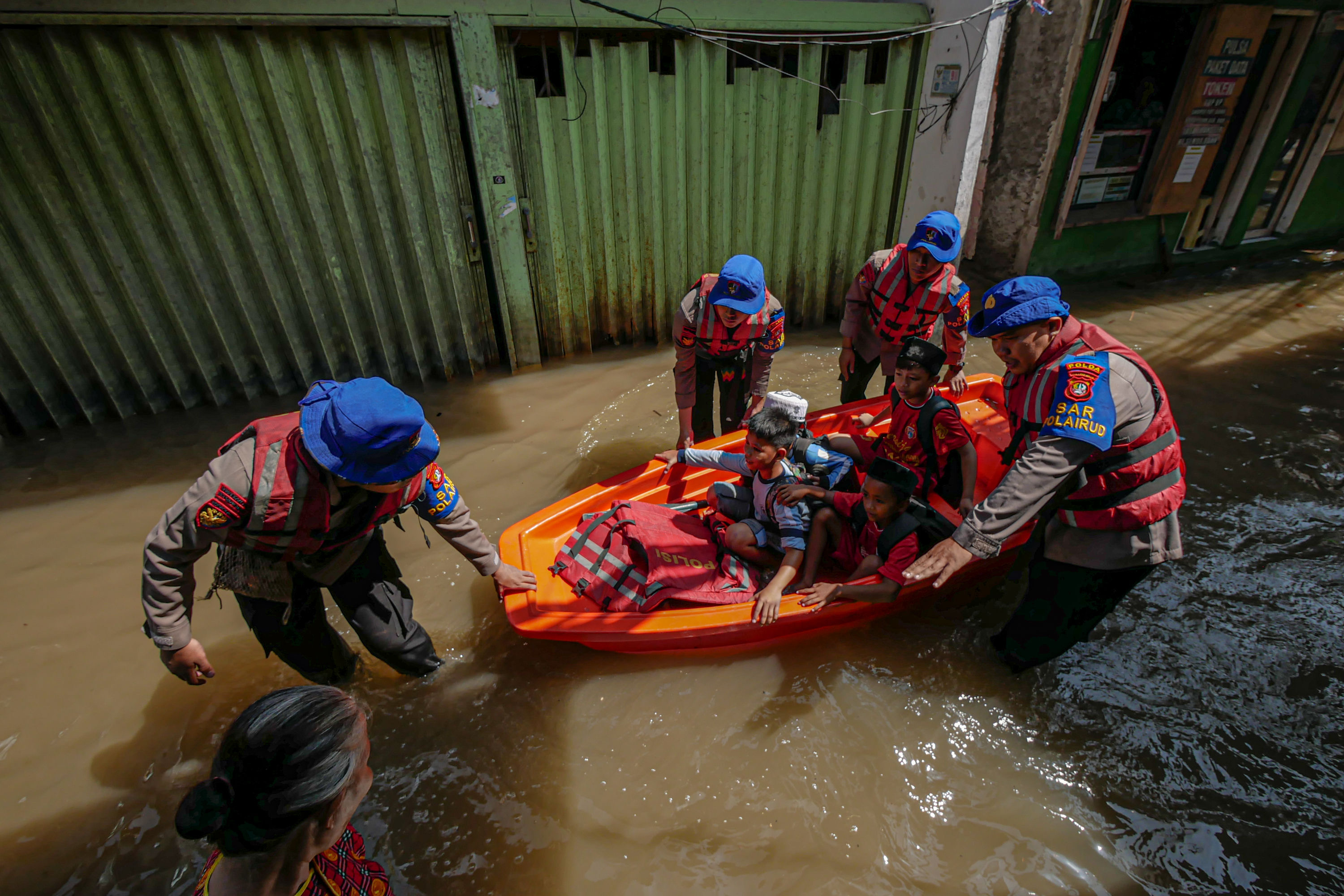 Personel Polairud mengantar siswa yang pulang sekolah dengan perahu di banjir rob yang mulai meninggi di kawasan Muara Angke, Jakarta Utara.