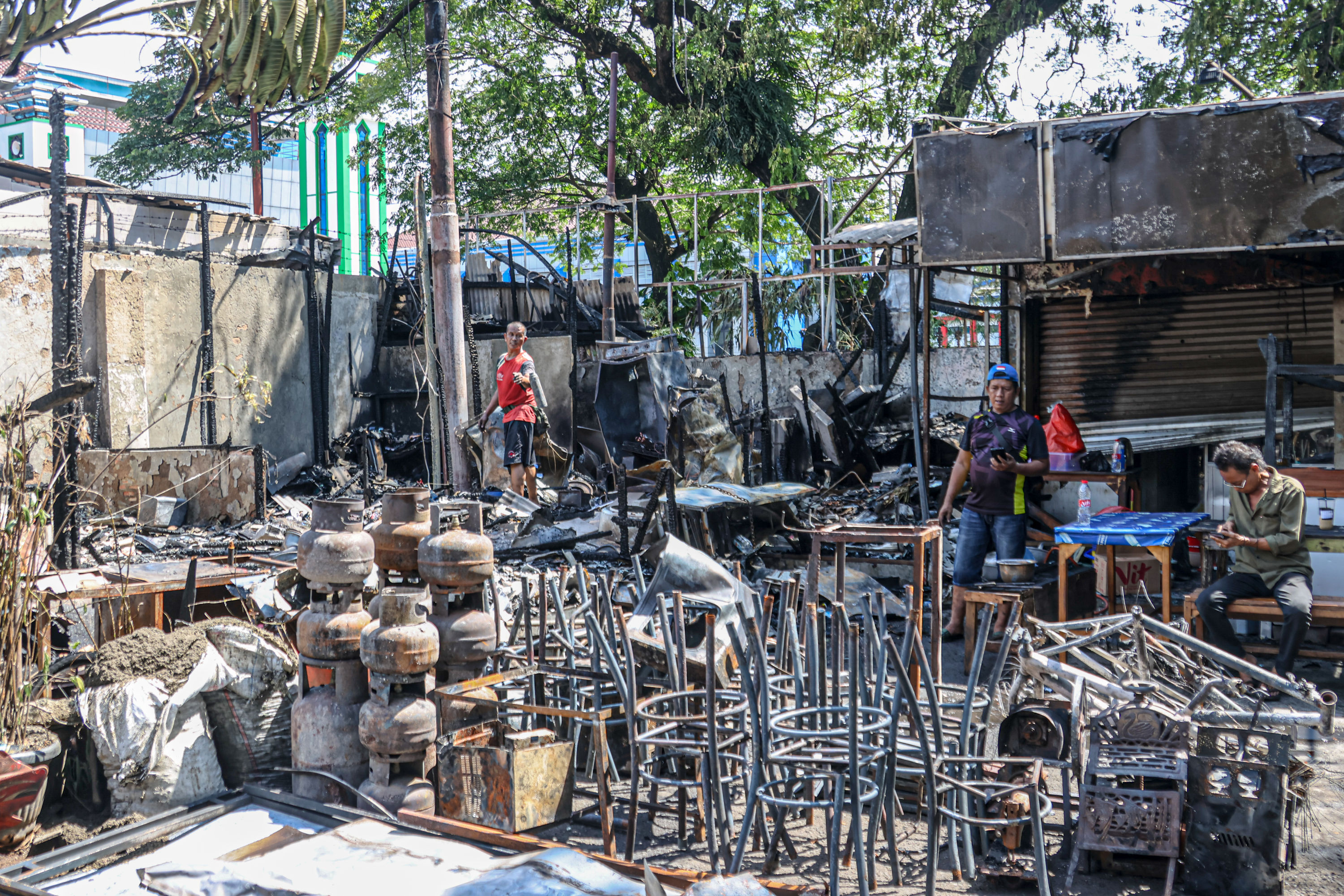 Petugas PPSU membersihkan area pasca terbakarnya kios di Sentra Kuliner kalibata, Jakarta Selatan.