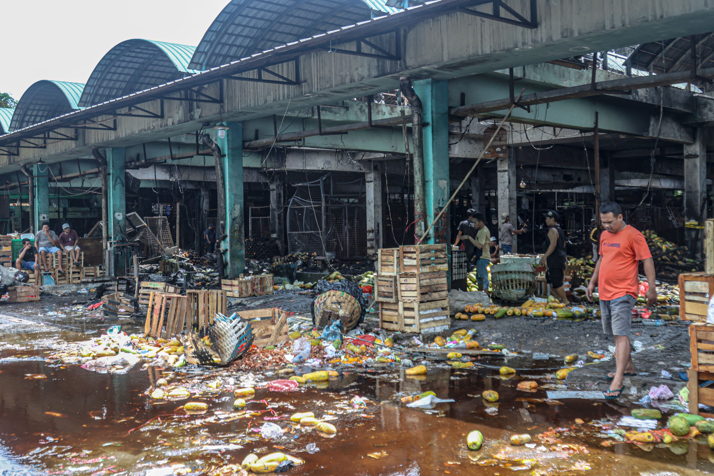 Pedagang mengevakuasi barang dagangannya berupa buah-buahan pasca kebakaran yang menghanguskan kios di Pasar Kramat Jati, Jakarta Timur, Senin (15/12).