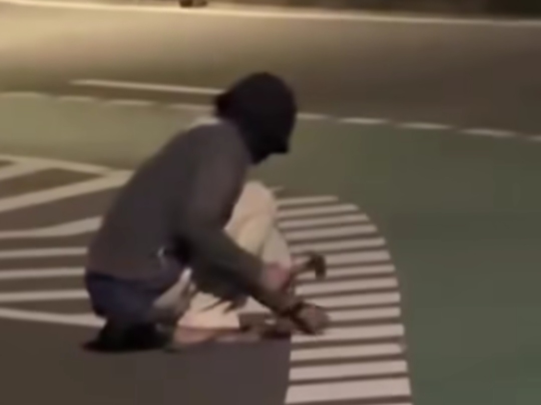 Seorang pria bermasker tertangkap kamera sedang asyik mencongkel road stud atau mata kucing marka jalan di kawasan Cawang, Jakarta Timur. (Istimewa)