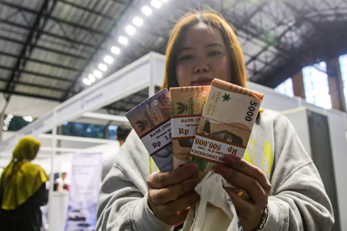 Warga menunjukan uang rupiah usai melakukan penukaran uang baru pada Layanan Penukaran Terpadu Bank Indonesia dan Perbankan di Hall Basket, Senayan, Jakarta, Jumat (21/3/2025).
